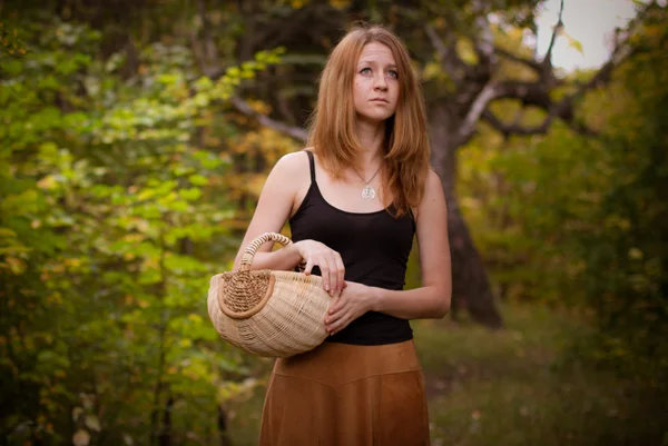 Vörös hajú fiatal lány, egy kosár, séta az erdőben — Stock Fotó