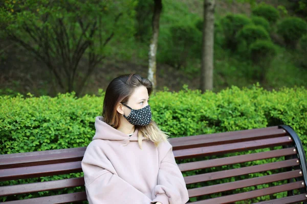 Young girl wearing designer face mask outside at the park at summer.  Reusable fashionable face mask.