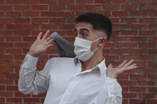 レンガの壁の前で驚く医療用マスクをした若い男性の肖像画 — ストック写真