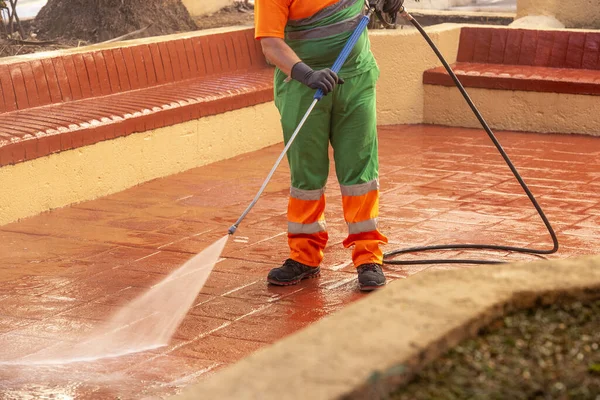 A worker cleaning the streets with a pressurized bleach water gun - the concept of coronavirus prevention