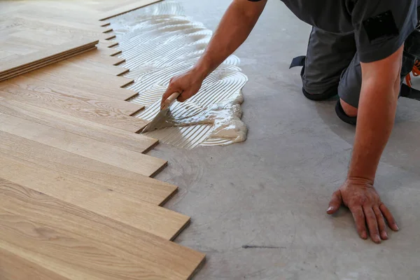 Een Mannelijke Arbeider Die Een Houten Laminaatvloer Zijn Knieën Installeert — Stockfoto