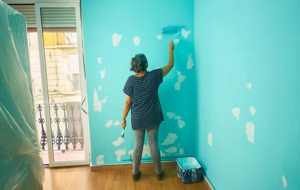 Μια Ενήλικη Γυναίκα Ζωγραφίζει Ένα Κυανό Χρώμα Τοίχου Έναν Κύλινδρο — Φωτογραφία Αρχείου