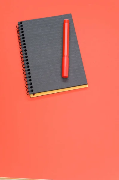 Colpo Verticale Notebook Nero Pennarello Rosso Una Superficie Rossa — Foto Stock