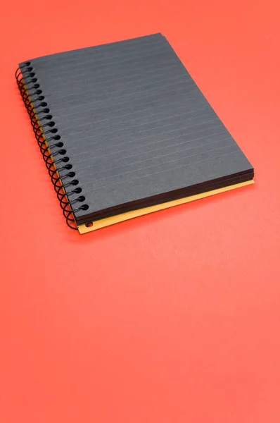 Plano Vertical Cuaderno Negro Sobre Una Superficie Roja —  Fotos de Stock