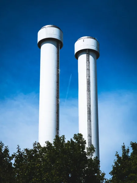 青い空の背景にある2つの水の塔の垂直ショット — ストック写真