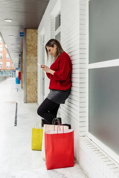 Tiro Vertical Uma Jovem Usando Seu Telefone Deixando Sacos Papel — Fotografia de Stock