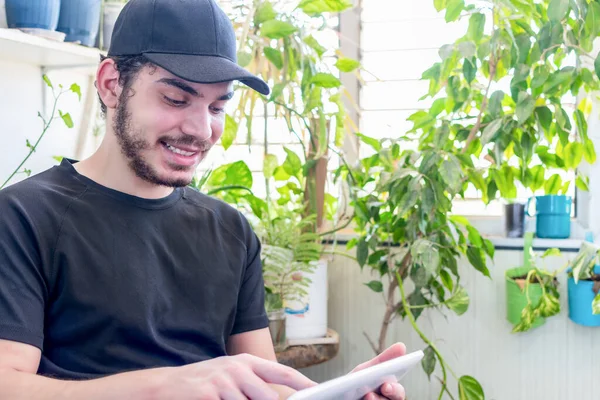 Joven Caucásico Con Una Gorra Barba Usando Una Tableta Mientras — Foto de Stock