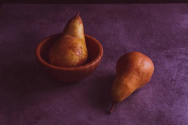 二つの梨の一つを木の鉢に閉じ もう一つは紫色の効果を加えたものです — ストック写真