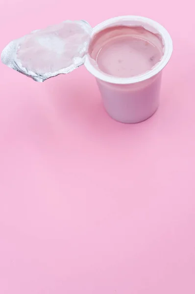 Вертикальний Знімок Відкритої Пластикової Ємності Фруктового Йогурту Рожевій Поверхні — стокове фото