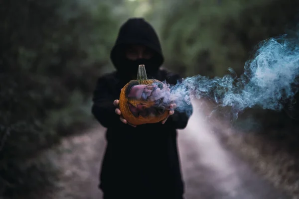 オレンジの煙が出てくる彫刻カボチャを持っている男 ハロウィーンの概念 — ストック写真
