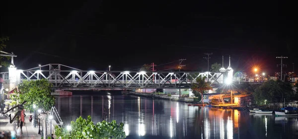Panoramiczny Widok Podświetlanego Mostu Kolejowego Nad Spokojną Rzeką Odbiciami Światła — Zdjęcie stockowe