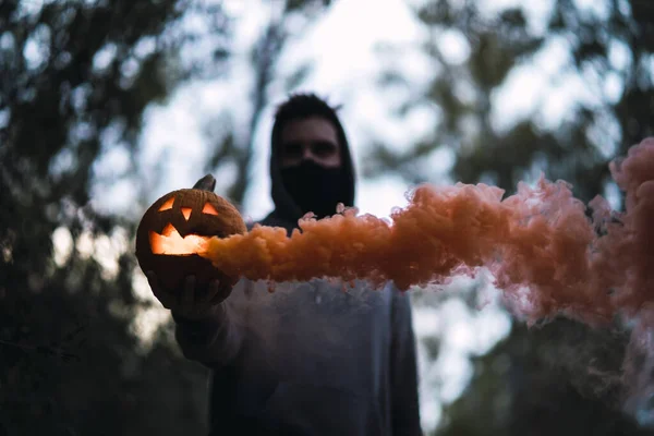 オレンジの煙が出てくる彫刻カボチャを持っている男 ハロウィーンの概念 — ストック写真