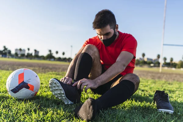 Fotbollsspelare Mask Sitter Gräsmattan Och Binda Skosnören Begreppet Hälsosam Livsstil — Stockfoto