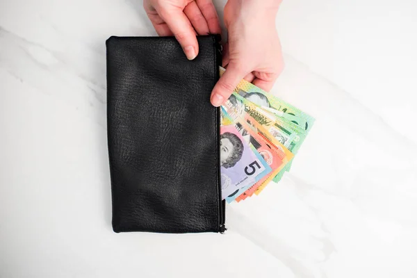the Australian dollar banknotes in a black wallet on the white background
