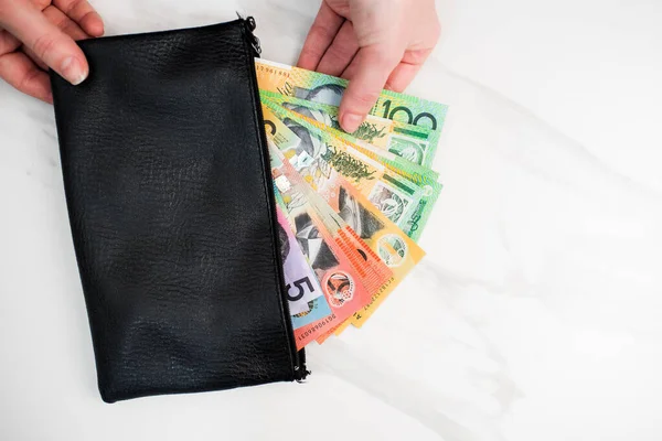 the Australian dollar banknotes in a black wallet on the white background