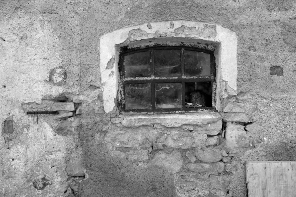 Graustufenaufnahme Eines Kleinen Zerbrochenen Fensters Eines Verlassenen Gebäudes Bei Tag — Stockfoto