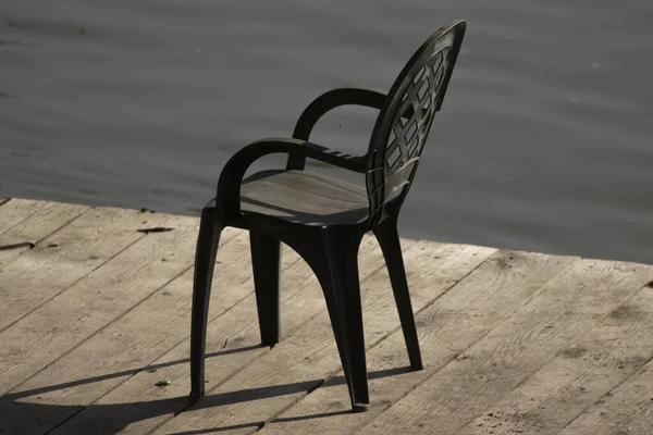 ドックに捨てられた黒いプラスチック製の椅子 — ストック写真