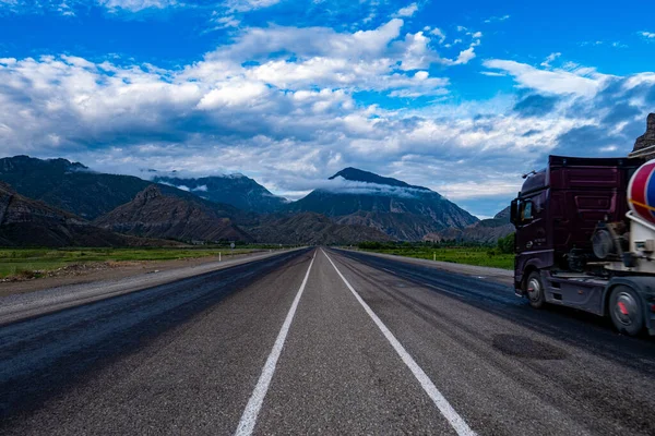 Grande Caminhão Dirigindo Estrada Cercado Pelas Montanhas Sob Céu Nublado — Fotografia de Stock
