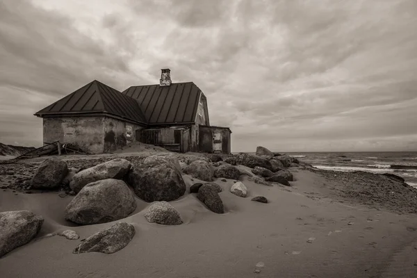 Stary Dom Plaży Otoczony Skałami Morzem Pod Zachmurzonym Niebem Monochromatycznych — Zdjęcie stockowe