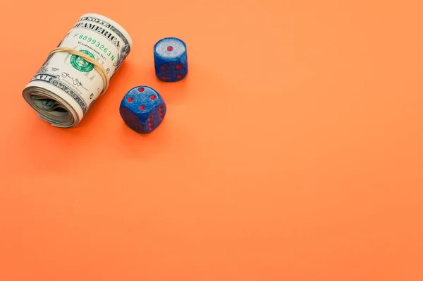 Een Bundel Opgerolde Amerikaanse Bankbiljetten Twee Blauwe Dobbelstenen Geïsoleerd Oranje — Stockfoto