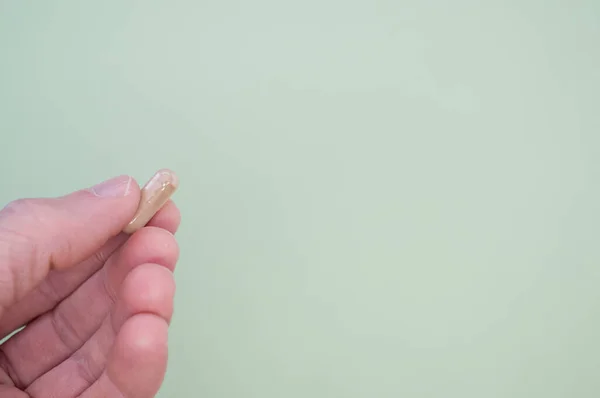 Uma Mão Segurando Uma Cápsula Fundo Verde Pastel Com Espaço — Fotografia de Stock