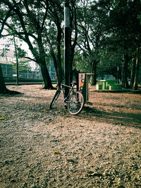 ポストの近くの公園に停められた自転車の垂直ショット — ストック写真