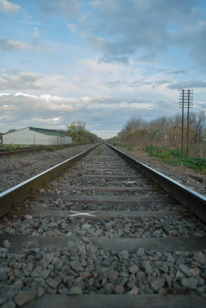 曇りの空の下で列車のレールの垂直ショット — ストック写真