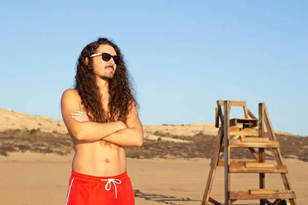 在海滩上 一个留着长长的卷发 戴着太阳镜的有魅力年轻人的特写镜头 — 图库照片