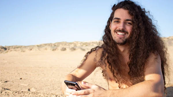 ビーチで長い巻き毛の魅力的な若い男のクローズアップショット — ストック写真