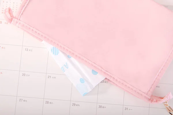 A sanitary pad in a cosmetic bag on a calendar