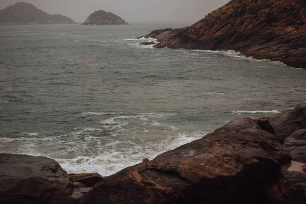 岩の多い海岸近くで砕ける大きな泡の波の接近ショット — ストック写真
