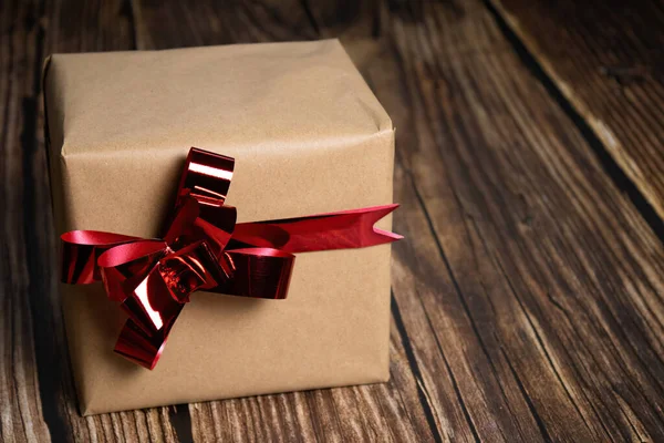 红带礼品盒的特写木制背景上有红带的礼品盒的特写 — 图库照片