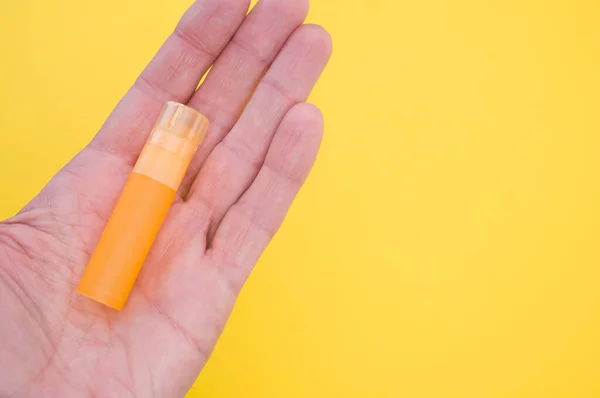 Una Mano Sosteniendo Pequeño Tubo Plástico Vacío Color Naranja Sobre —  Fotos de Stock