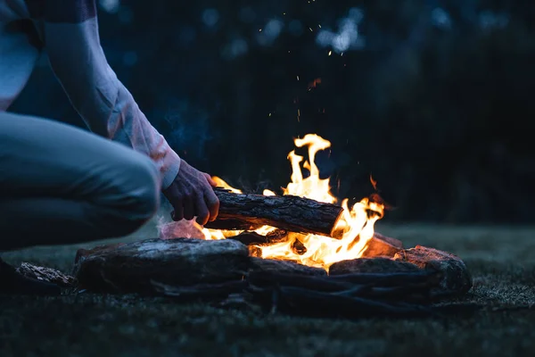 Ein Mann Legt Abends Einen Baumstamm Ein Lagerfeuer — Stockfoto