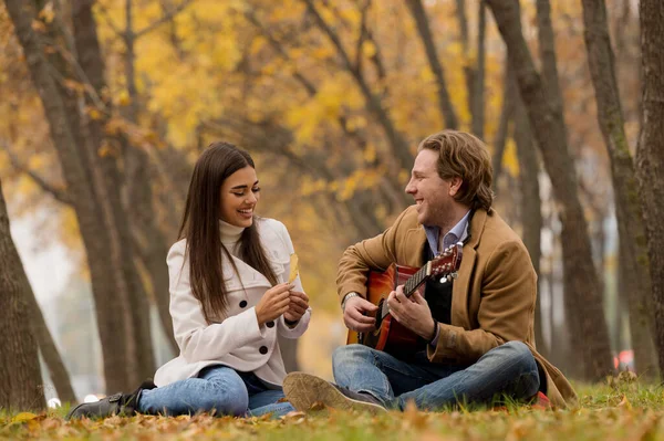 Feliz Casal Caucasiano Sentado Grama Tocando Guitarra Parque Outono — Fotografia de Stock