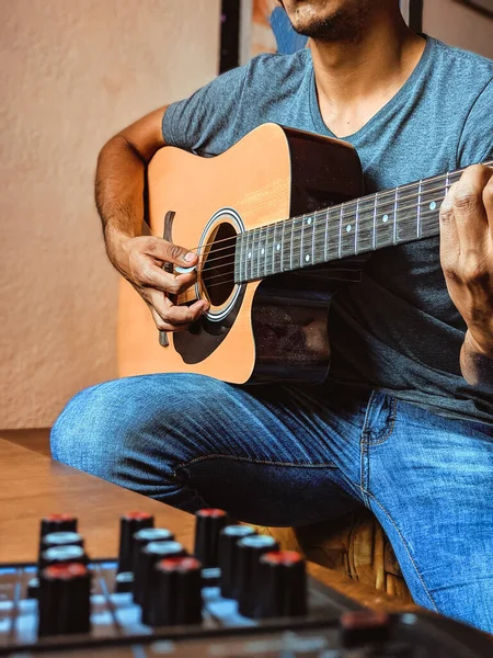 A vertical shot of a male playing on guitar