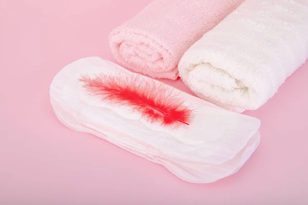 卫生巾上的红色羽毛和粉色背景的浴巾 — 图库照片