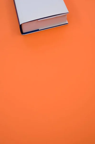 オレンジの背景に隔離された白い本の垂直上のビューショット コピースペース — ストック写真
