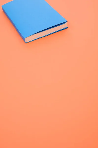 オレンジ色の表面に青いハードカバーの本の閉鎖 テキストのためのスペース — ストック写真