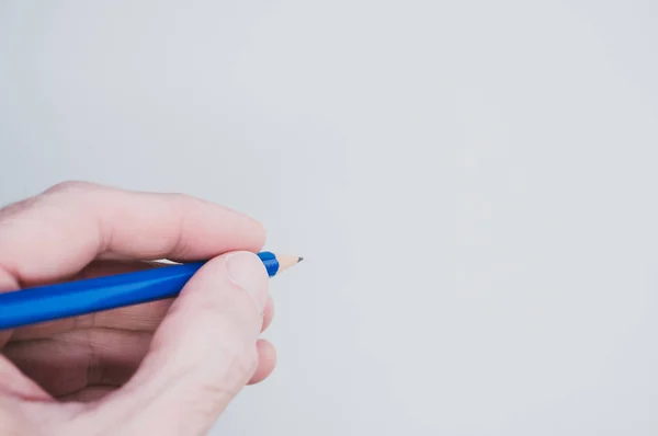 Una Mano Che Tiene Una Matita Blu Sfondo Grigio Uno — Foto Stock