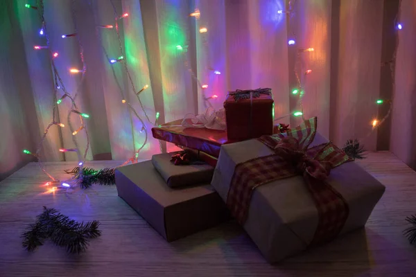 Uma Pilha Presentes Natal Uma Mesa Madeira Com Luzes Coloridas — Fotografia de Stock