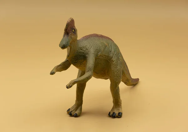 A closeup of a plastic dinosaur toy isolated on beige background