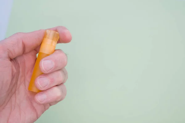 Een Hand Met Een Leeg Klein Oranje Plastic Buisje Pastelgroene — Stockfoto