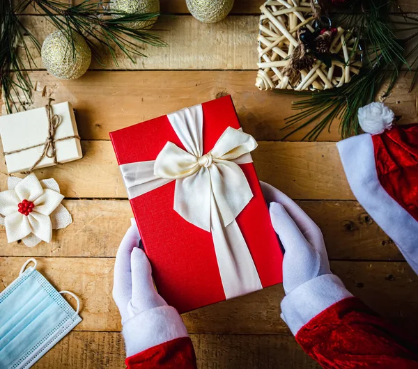 Egy Közelkép Fehér Kesztyűs Kezekről Karácsonyi Ajándékkal Dekorációval Egészségügyi Maszkkal — Stock Fotó