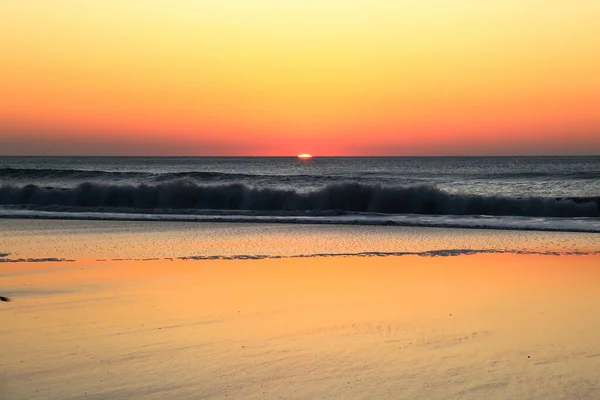 Ein Sandstrand Und Welliges Meer Bei Sonnenuntergang — Stockfoto