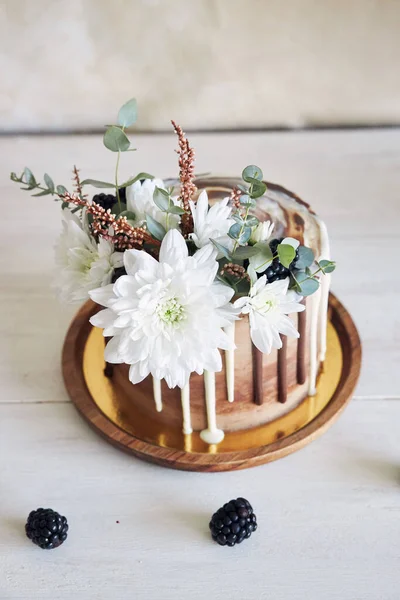 テーブルの上に花やブラックベリーと白と茶色のチョコレートとおいしいケーキが渦巻く — ストック写真