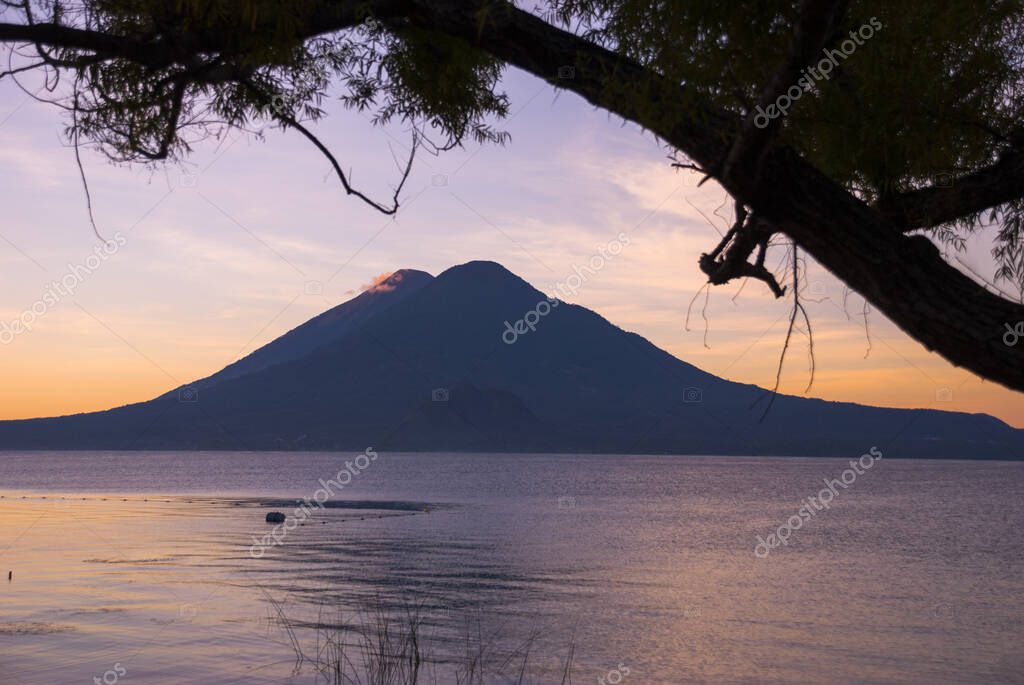 Salida del sol frente al lago Atitlán en Guatemala y volcán en el fondo