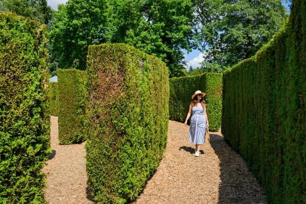 公園内のプライベート ヘッジの植物と一緒に帽子を歩く白人女性 — ストック写真