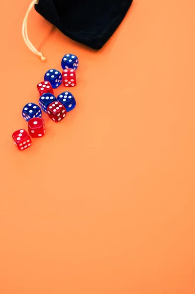 一个垂直的红色和蓝色骰子拍摄在一个用橙色背景隔开的骰子袋上 — 图库照片