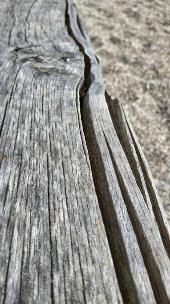 公園で傷を負った古い木製のベンチの垂直ショット — ストック写真